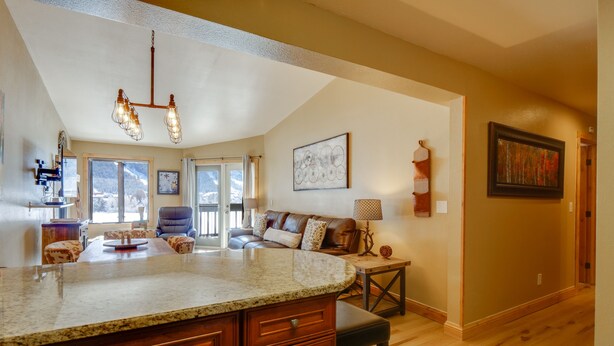 A spacious kitchen with a large island, a dining area with a brown leather couch, and a living room with a fireplace. - Walk to Copper Mountain Lifts: Mtn-View Condo (Copper Mountain)