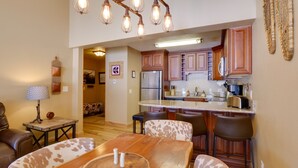 A modern kitchen with wooden cabinets, a central island, and a dining area with a wooden table and chairs. - Walk to Copper Mountain Lifts: Mtn-View Condo (Copper Mountain)