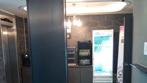 A modern lobby with a vending machine, a refrigerator, and a wall-mounted security camera.