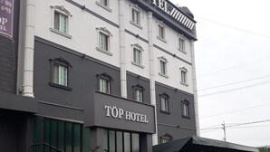 A hotel with a sign reading "TOP HOTEL" and a parking sign indicating disabled parking.