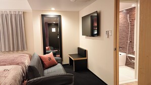 Ein Hotelzimmer mit Bett, Sofa, Fernseher und einer Duschkabine.