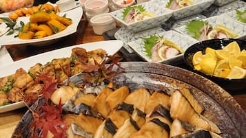 A variety of dishes including seafood, vegetables, and possibly some meat, arranged on a table.