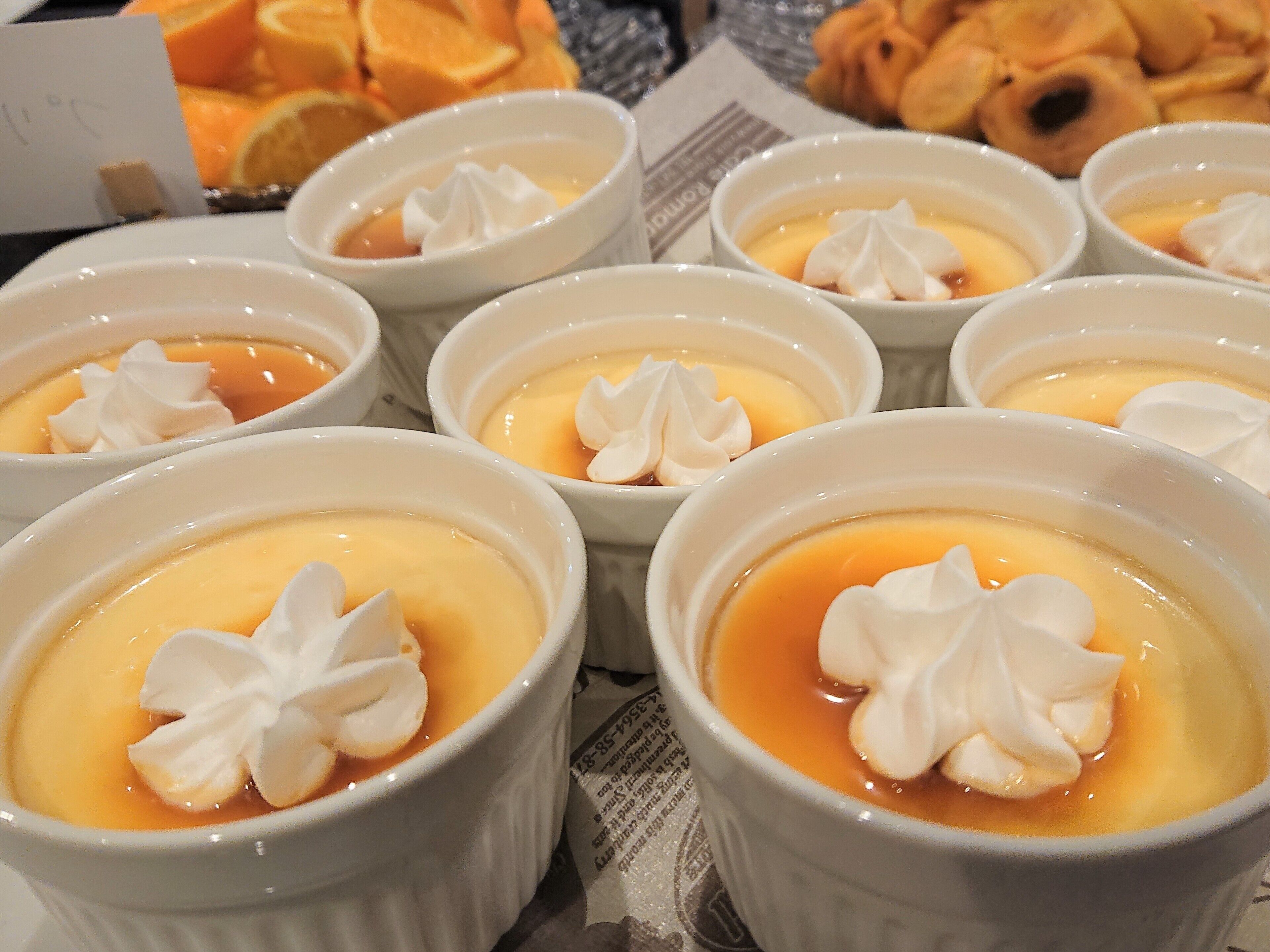 A table with multiple ramekins of crème brûlée, each topped with a dollop of whipped cream.