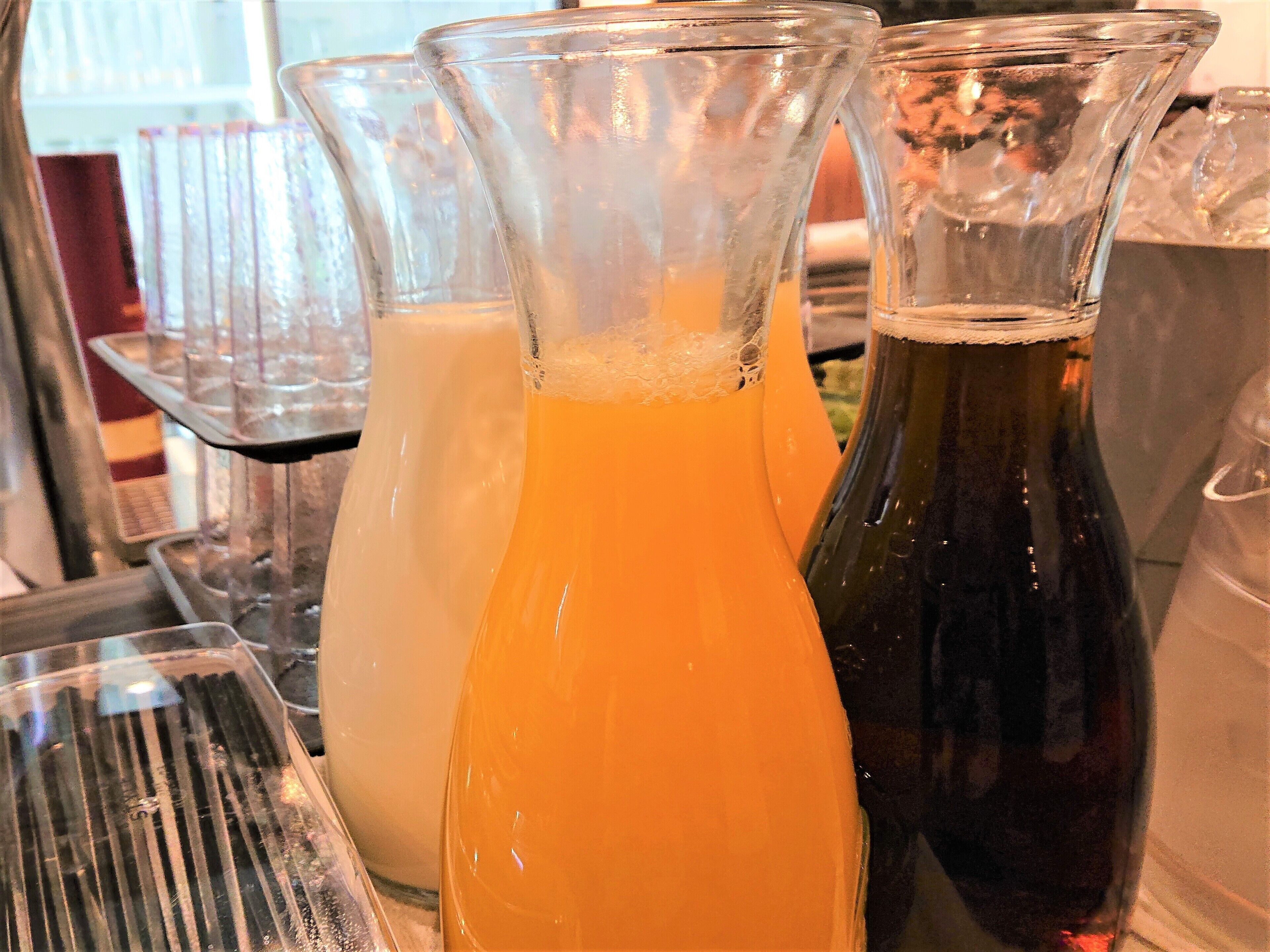Trois bouteilles en verre contenant des liquides de couleurs différentes, vraisemblablement des boissons, sont posées sur une surface métallique.
