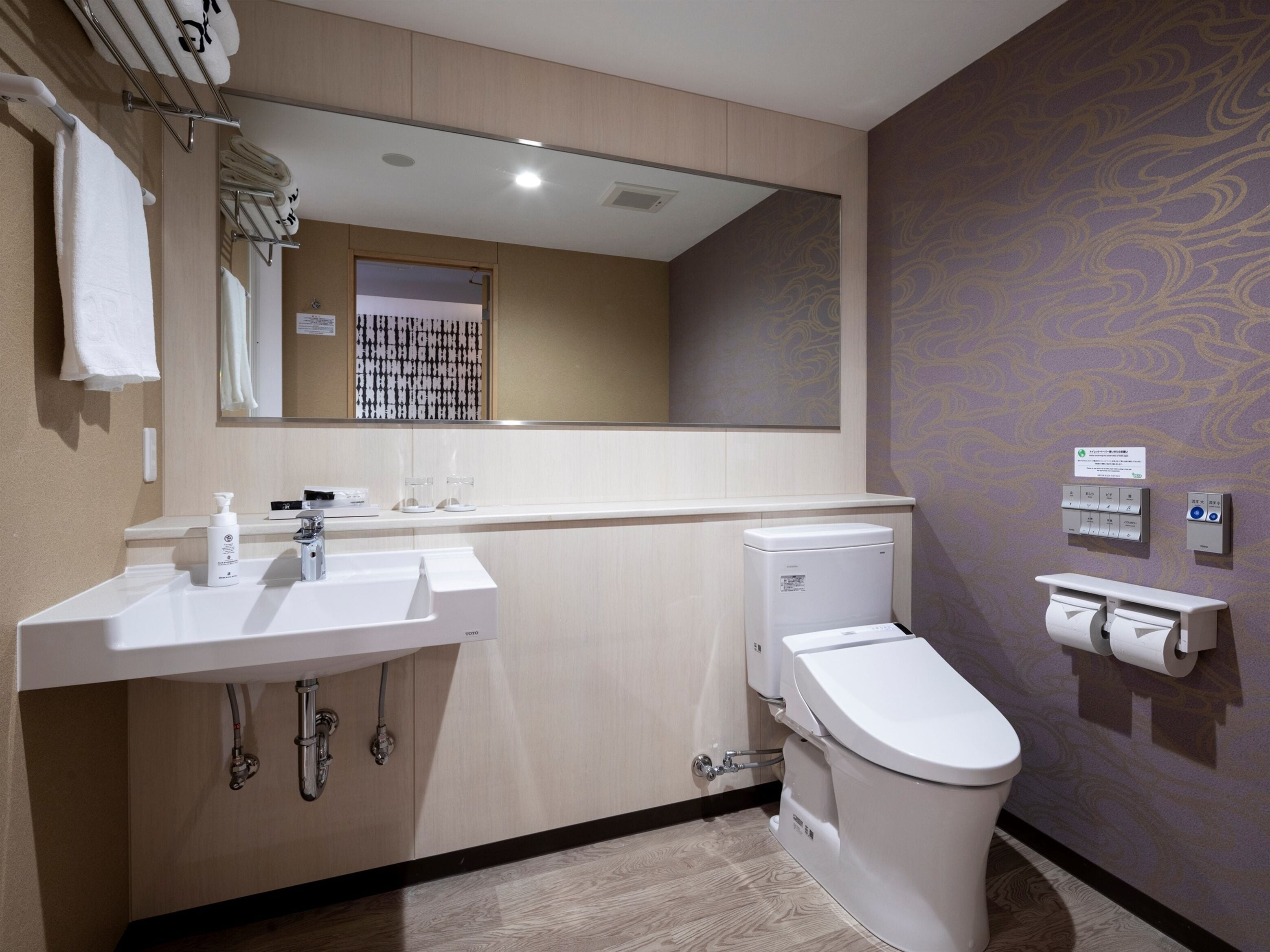 A modern bathroom with a white sink, a toilet, and a mirror above the sink.