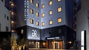 Ein modernes Hotel mit einem auffälligen Schild 'Green Rich Hotels', einem Restaurant 'Teppan Dining Yuu' und einem Parkplatzschild.
