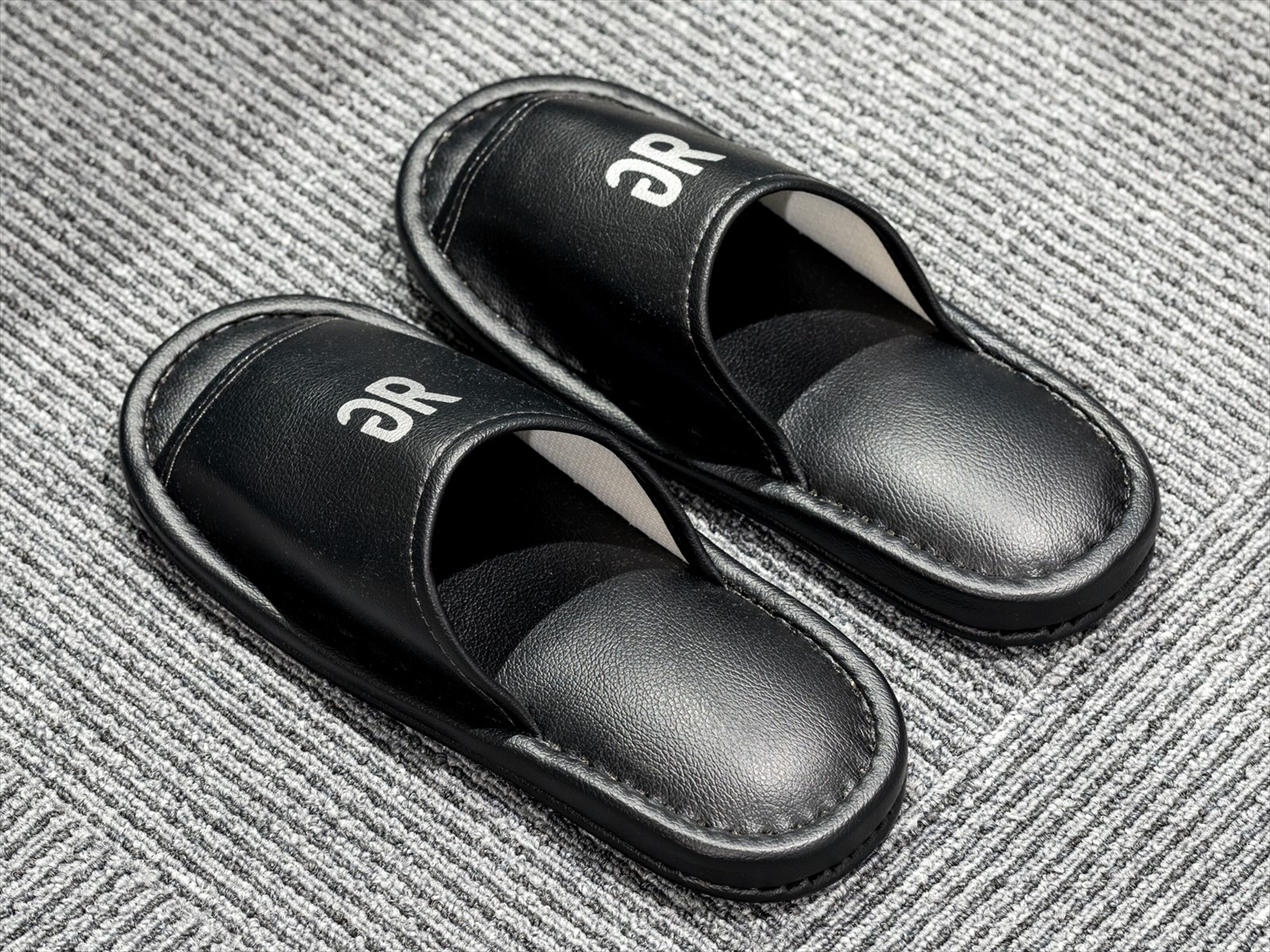 A pair of black slippers with a logo on the top.