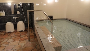 Ein Hotelbad mit gefliestem Boden, einer Marmorplatte, einem Waschbecken und einem kleinen Pool.