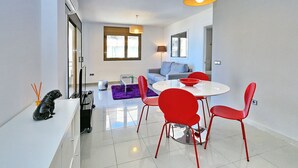 Ein modernes Wohnzimmer mit Essbereich, weißen Wänden und einem großen Fenster.