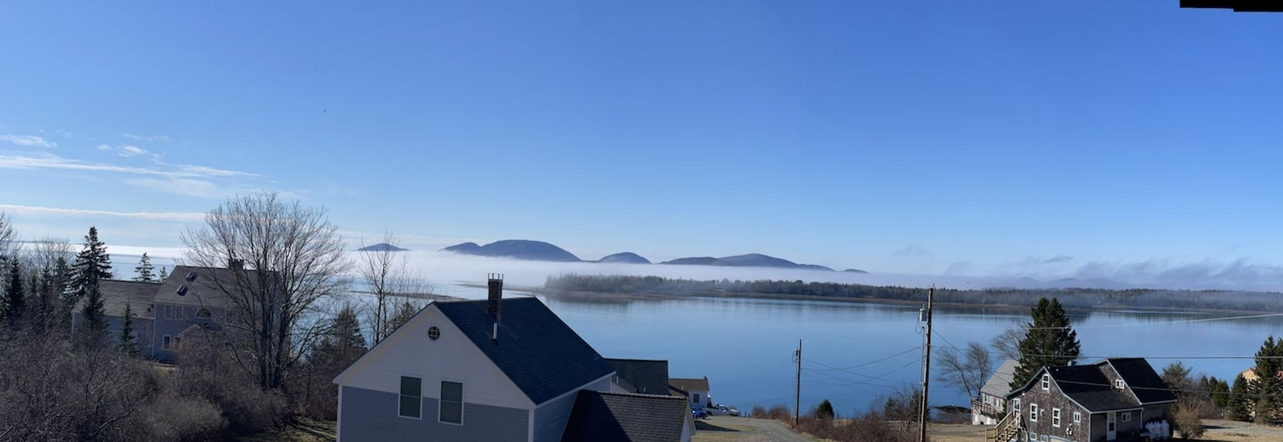 Une vue sur le lac, avec des maisons, un ciel dégagé et des montagnes à l’horizon.