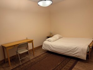 Ein Schlafzimmer mit einem Bett, einem Schreibtisch, einem Stuhl und einem Nachttisch mit Lampe.