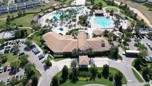 Vista aérea de un complejo turístico con varias piscinas, un edificio central y viviendas residenciales aledañas.