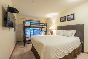 Una camera da letto con un letto a castello, un letto matrimoniale, una lampada e due quadri appesi al muro.