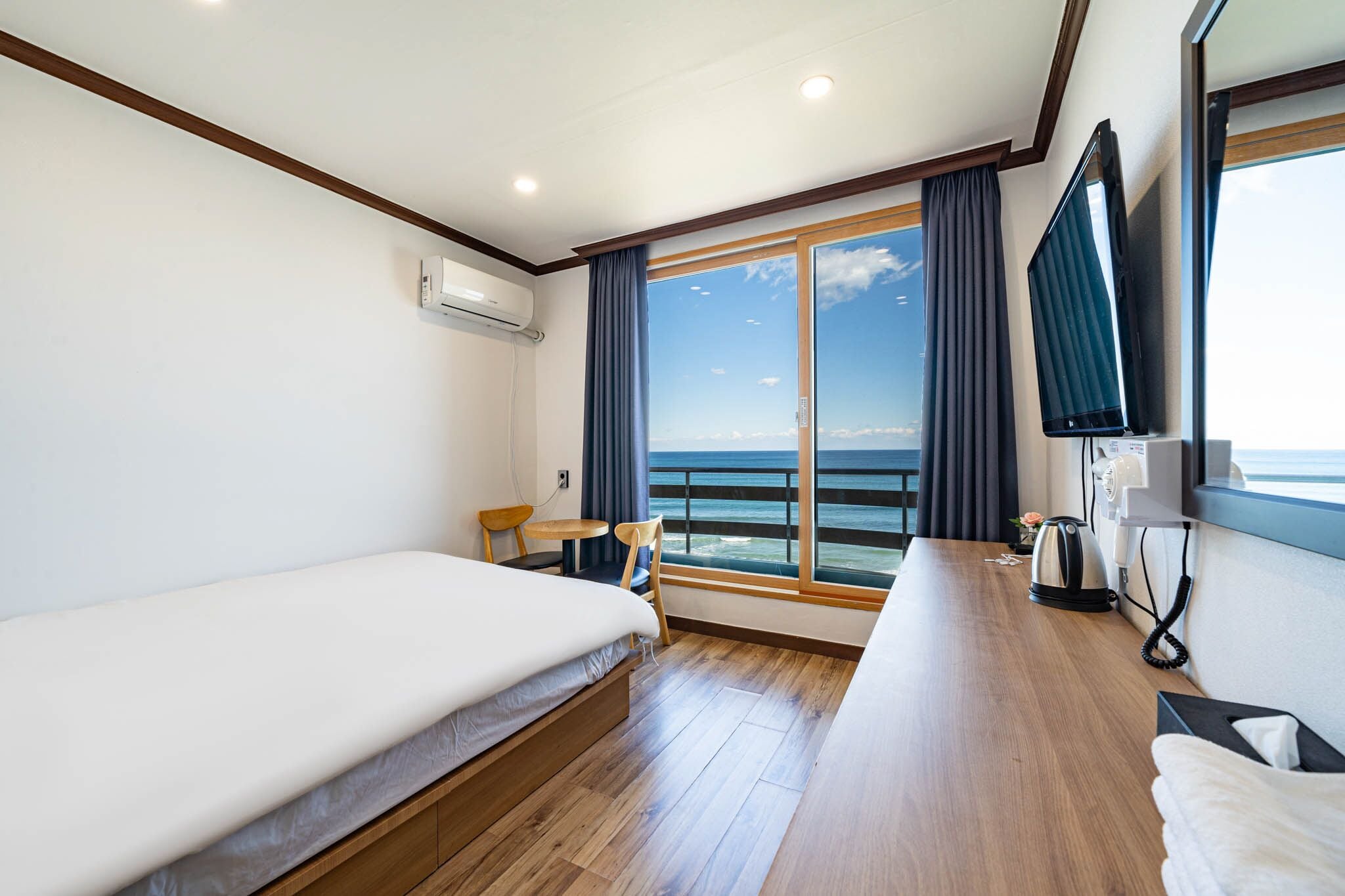 Habitación de hotel con cama, una mesita, una silla, televisor y vista al océano.