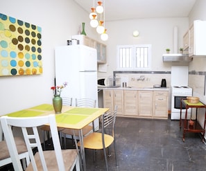 Cocina compacta con comedor, que incluye un refrigerador blanco, estufa y mesa con sillas.