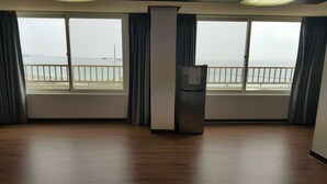 A spacious room with a large window offering a view of the sea. - Mangsang Beach Pension (Gangneung)