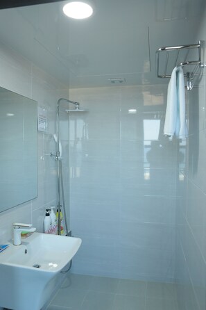 A modern bathroom with a glass-enclosed shower, a white sink, and a towel rack.
