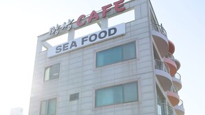 A multi-story building with a sign reading "Sea Food Cafe" and a storefront window. - Mangsang Beach Pension (Gangneung)
