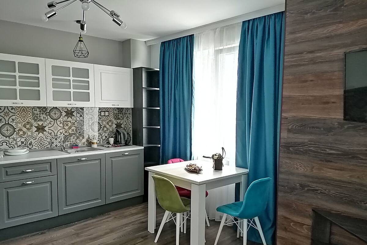 A modern kitchen with grey cabinets, a white countertop, and a dining area with a white table and two chairs.