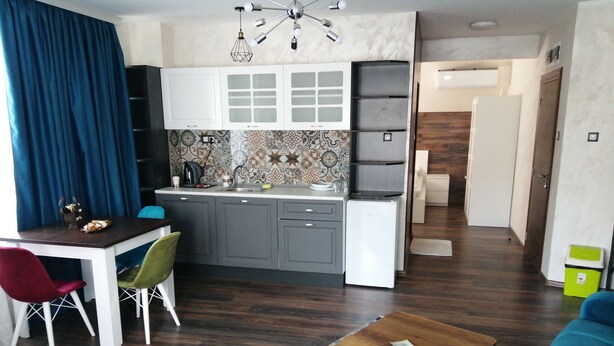 A compact living space with a dining area, kitchenette, and a small seating area with a coffee table. - The Old Bakery Apartments (Plovdiv)
