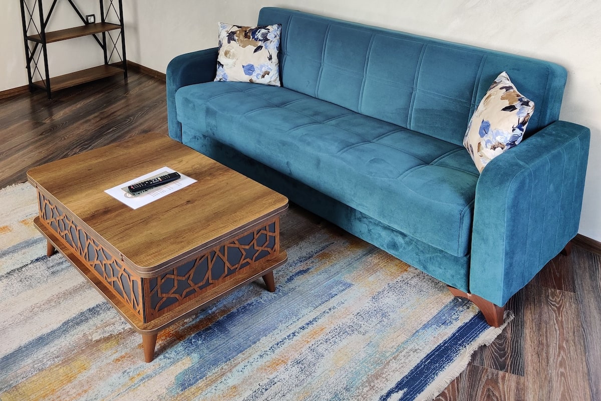 A room with a blue sofa, a wooden coffee table, and a patterned rug.