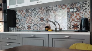 A kitchen with patterned tiles, a wooden table with food, and grey cabinets. - The Old Bakery Apartments (Plovdiv)