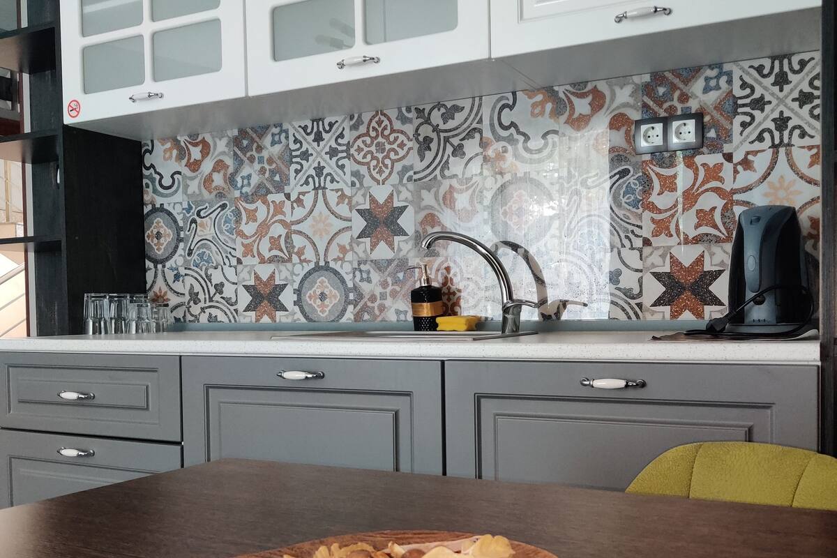 A kitchen with patterned tiles, a wooden table with food, and grey cabinets.