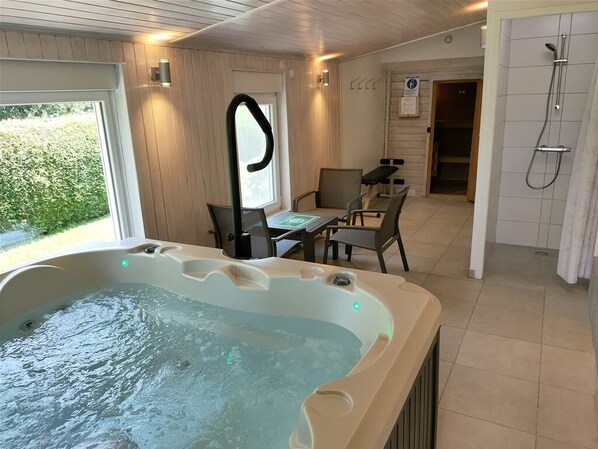 Une salle de bain avec un jacuzzi, une douche et une table avec des chaises.