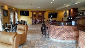 A hotel lobby with leather chairs, a bar area, and a dining section. - Hotel Cerro la Nina (Cangas de Onis)