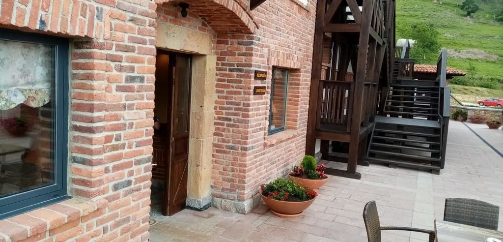 A brick building with a wooden staircase and a door. There are potted plants and a chair outside.
