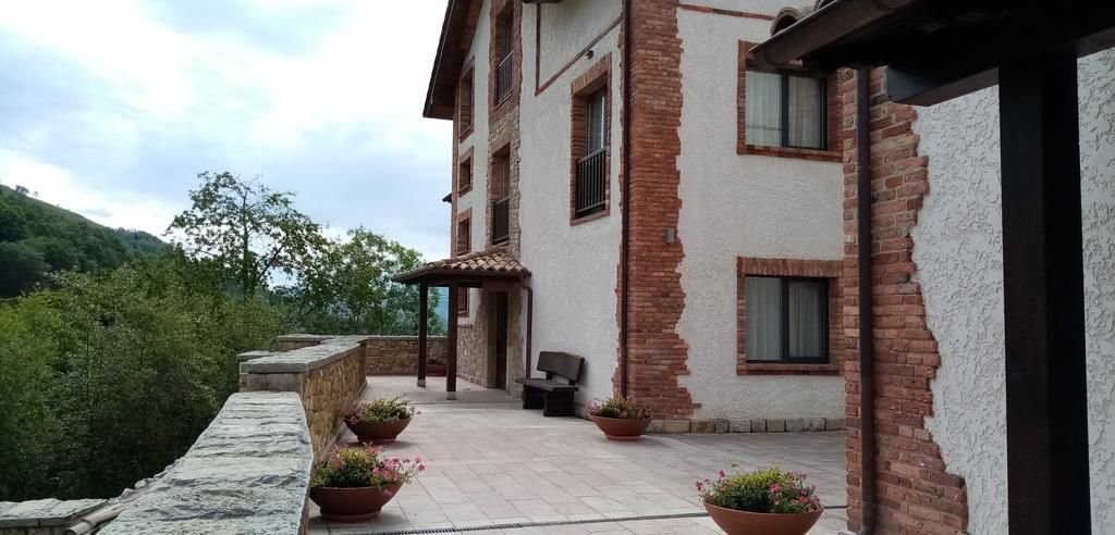 Un edificio con fachada de piedra, un patio cubierto con asientos y plantas en macetas.
