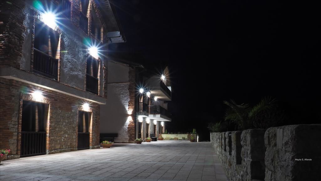 Un edificio con varias ventanas iluminadas y un acceso pavimentado.