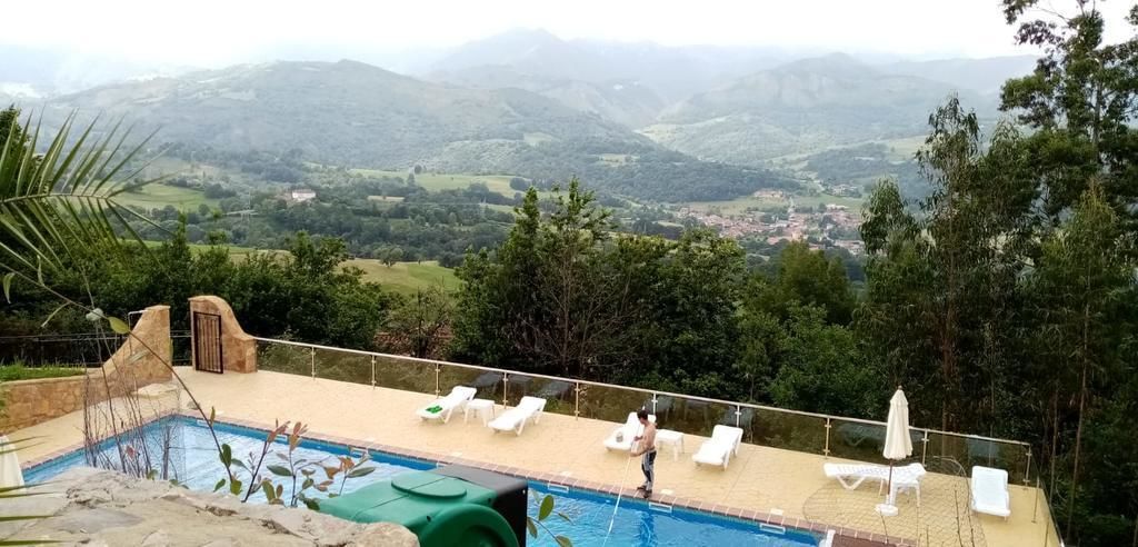 Zona de piscina con sillas de descanso y vistas del paisaje circundante.