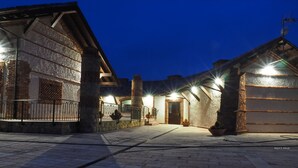 A stone building with a wooden facade, a gated entrance, and a paved courtyard. - Hotel Cerro la Nina (Cangas de Onis)