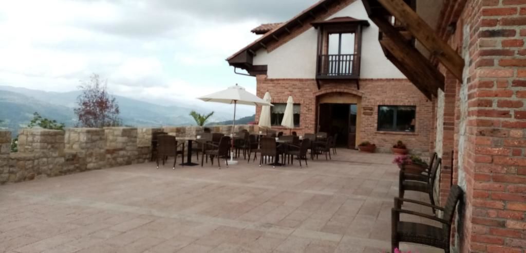 Une terrasse extérieure avec un sol en pierre, des tables, des chaises et des parasols.