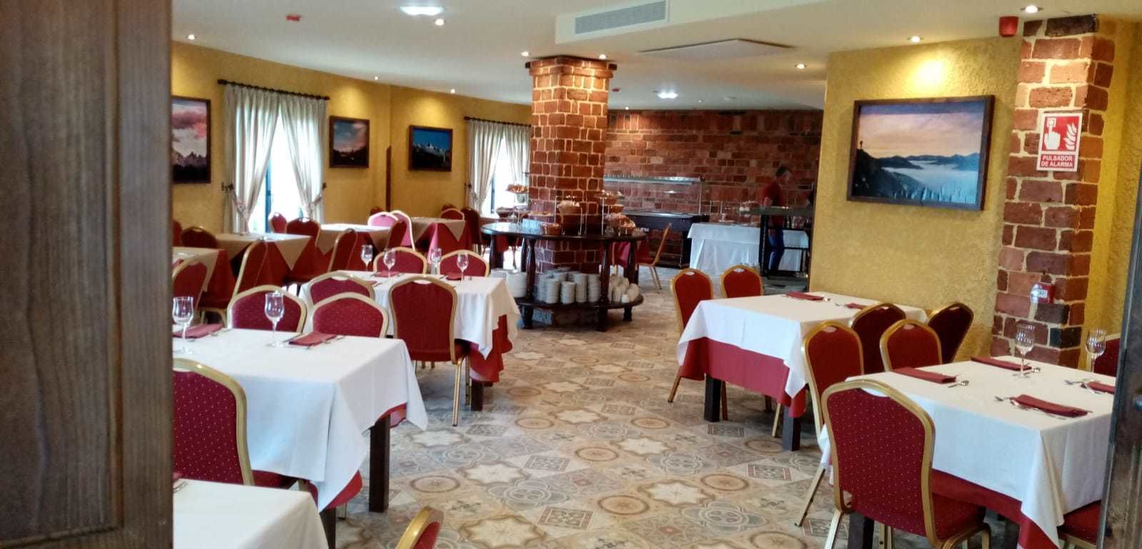 Un restaurante con varias mesas y sillas, paredes de ladrillo y una chimenea.