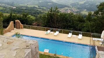 Una piscina con sillas de descanso y vistas al campo.