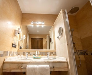 Un baño con dos lavamanos, un espejo, una ducha y un perchero para toallas.