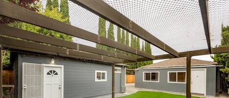 A backyard with a covered patio area, a garage, and a shed.