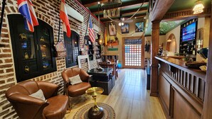 A cozy bar area with leather chairs, a wooden bar counter, and various flags. - Stay Shaandaar (Amritsar)