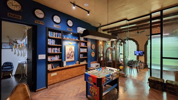 A room with a foosball table, bookshelves, clocks, and a TV. - Stay Shaandaar (Amritsar)