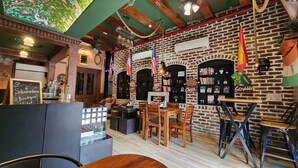 A cozy cafe with brick walls, wooden furniture, and a variety of books and games on shelves. - Stay Shaandaar (Amritsar)