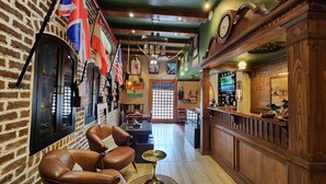A cozy bar area with leather chairs, a wooden bar counter, and various flags on the wall. - Stay Shaandaar (Amritsar)