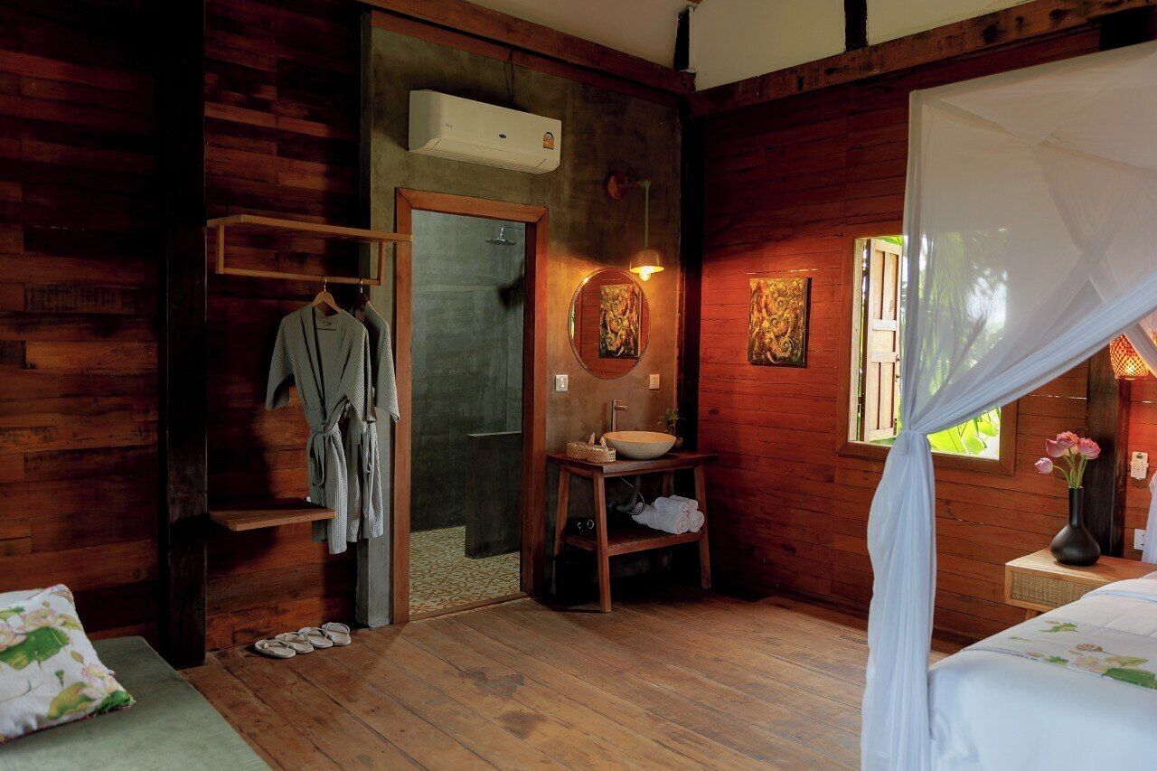 Una habitación de cabaña de madera con una cama, un baño con lavabo y espejo, y una ducha.