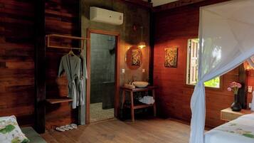 Una habitación de cabaña de madera con una cama, un baño con lavabo y espejo, y una ducha.