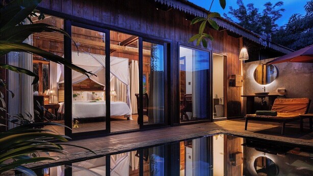 Uma villa moderna com um quarto envidraçado, piscina e área de refeições.