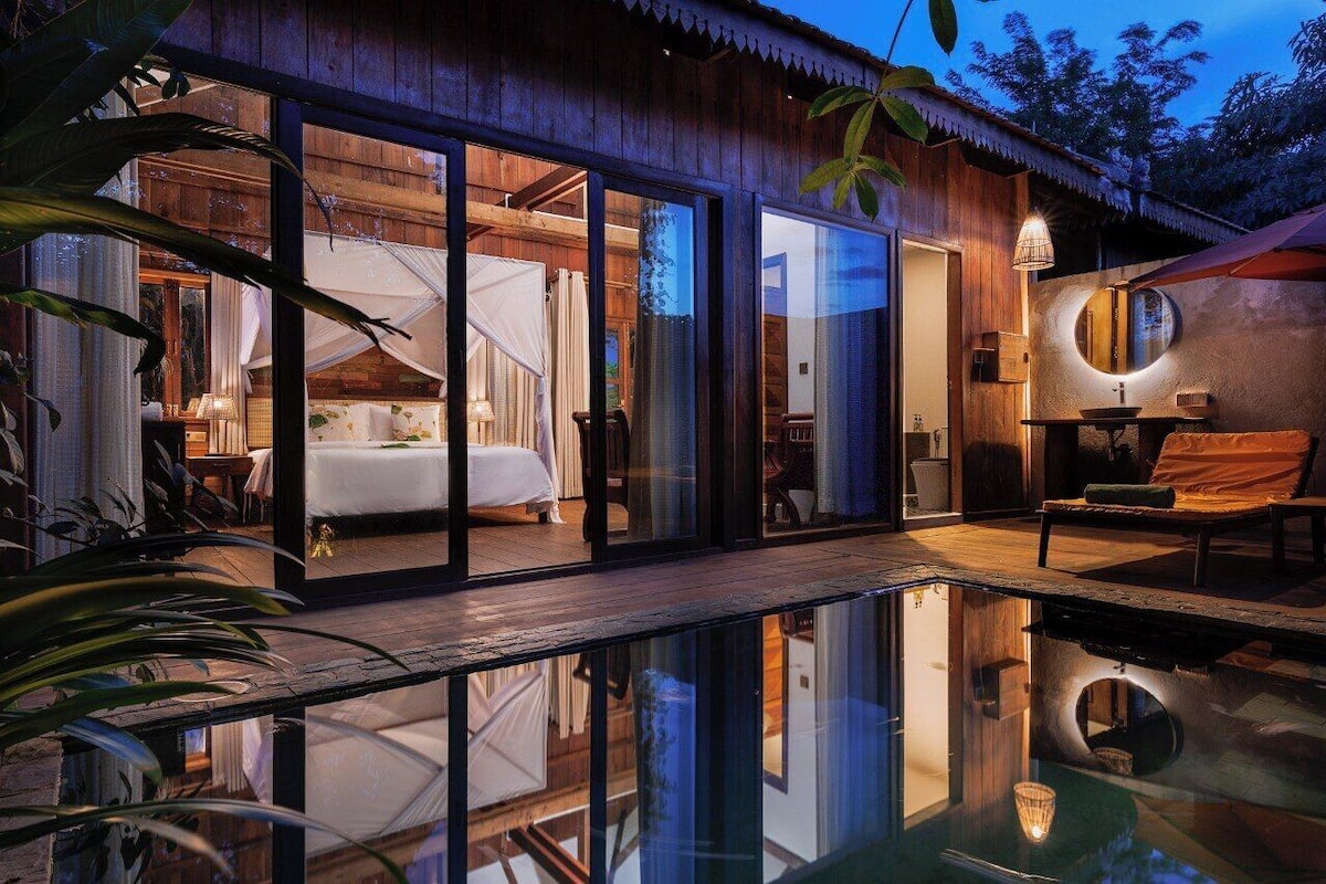 A modern villa with a glass-enclosed bedroom, a pool, and a dining area.