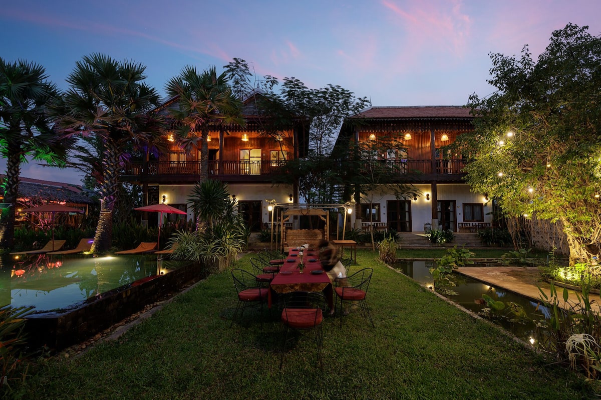 A two-story building with a pool, outdoor seating, and a well-maintained garden.