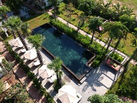 Una piscina al aire libre, sombrillas, sillones reclinables de piscina