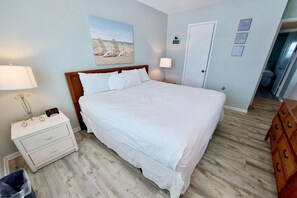 A neatly arranged bedroom with a large bed, bedside tables, a lamp, and a painting on the wall. - Harbor House B6 2 Bedroom Condo by RedAwning (Gulf Shores)